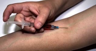Needle heald by blue gloved hand